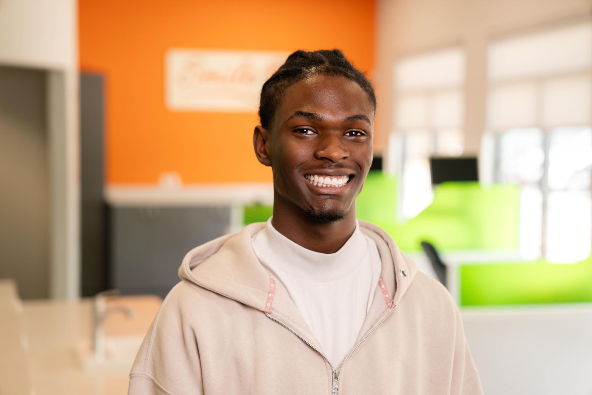 Smiling teen in casual hoodie showcasing a confident smile in a modern orthodontic office, highlighting the benefits of orthodontics for teens at Kraus Orthodontics.