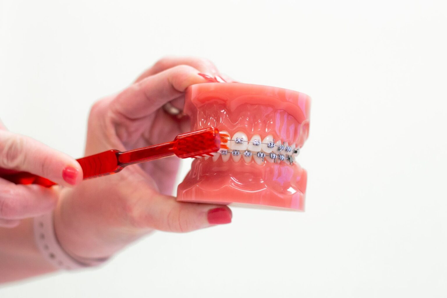 Hand holding a dental model with braces, demonstrating oral hygiene practices relevant to orthodontics in Allen, TX, highlighting care for children's smiles at Kraus Orthodontics.