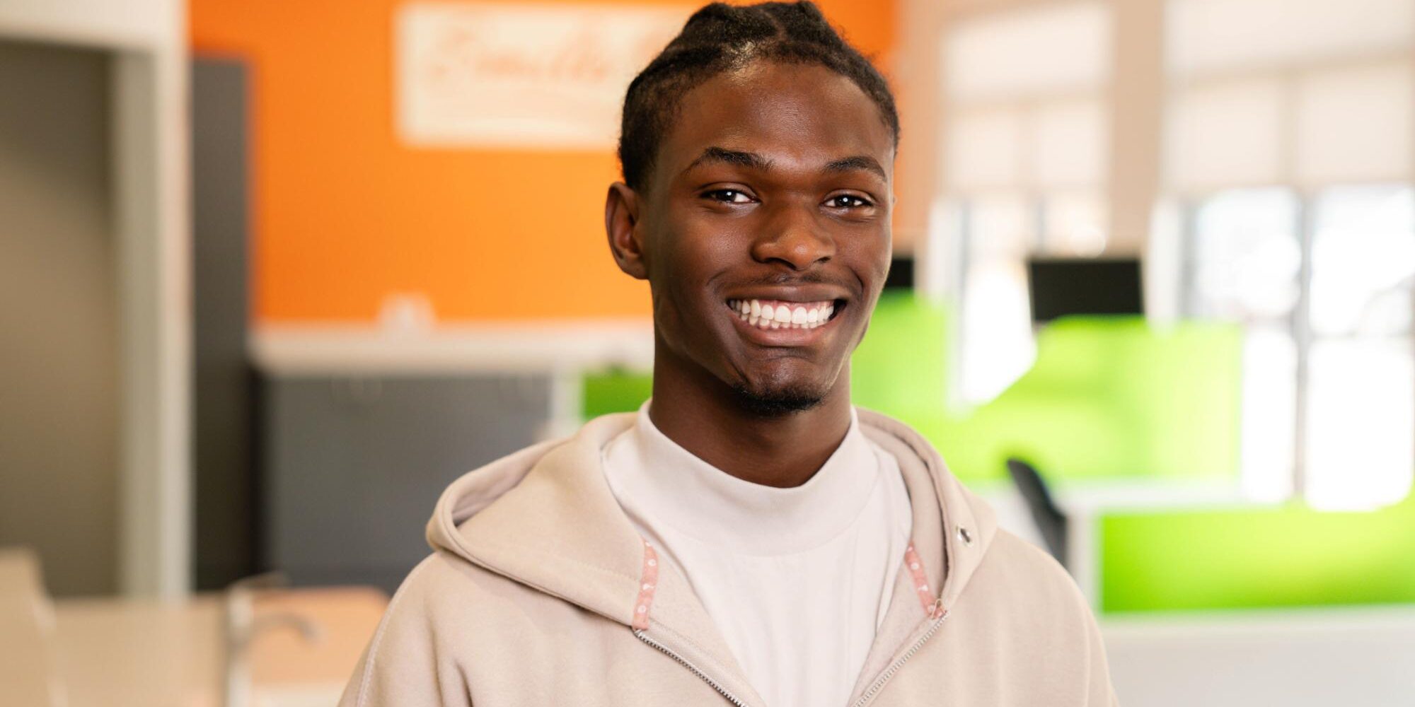 Smiling young man in a cozy orthodontic office, showcasing confidence and the benefits of clear aligners.